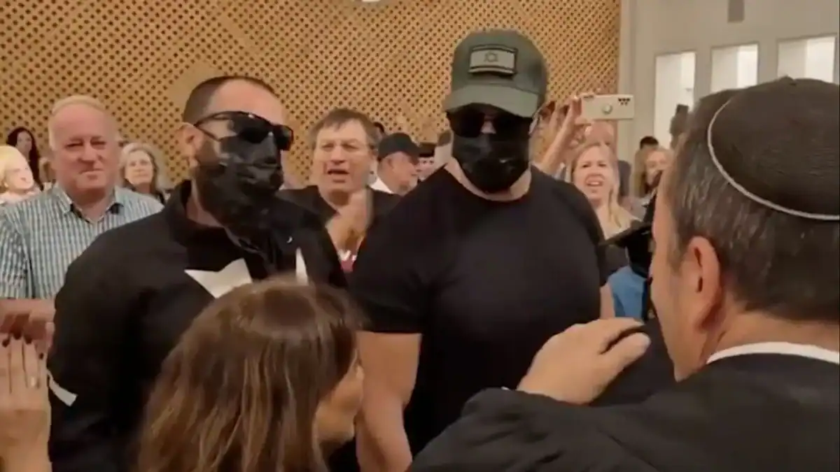 Masked Israeli soldiers accused of raping a Palestinian detainee stand in a Jerusalem courtroom as supporters applaud around them.