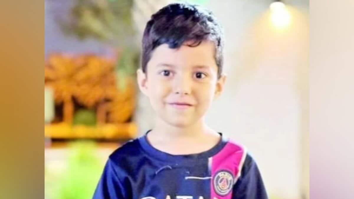 A 6-year-old boy, identified as Issa Al Zahir, smiling while wearing a dark T-shirt with pink and white accents.