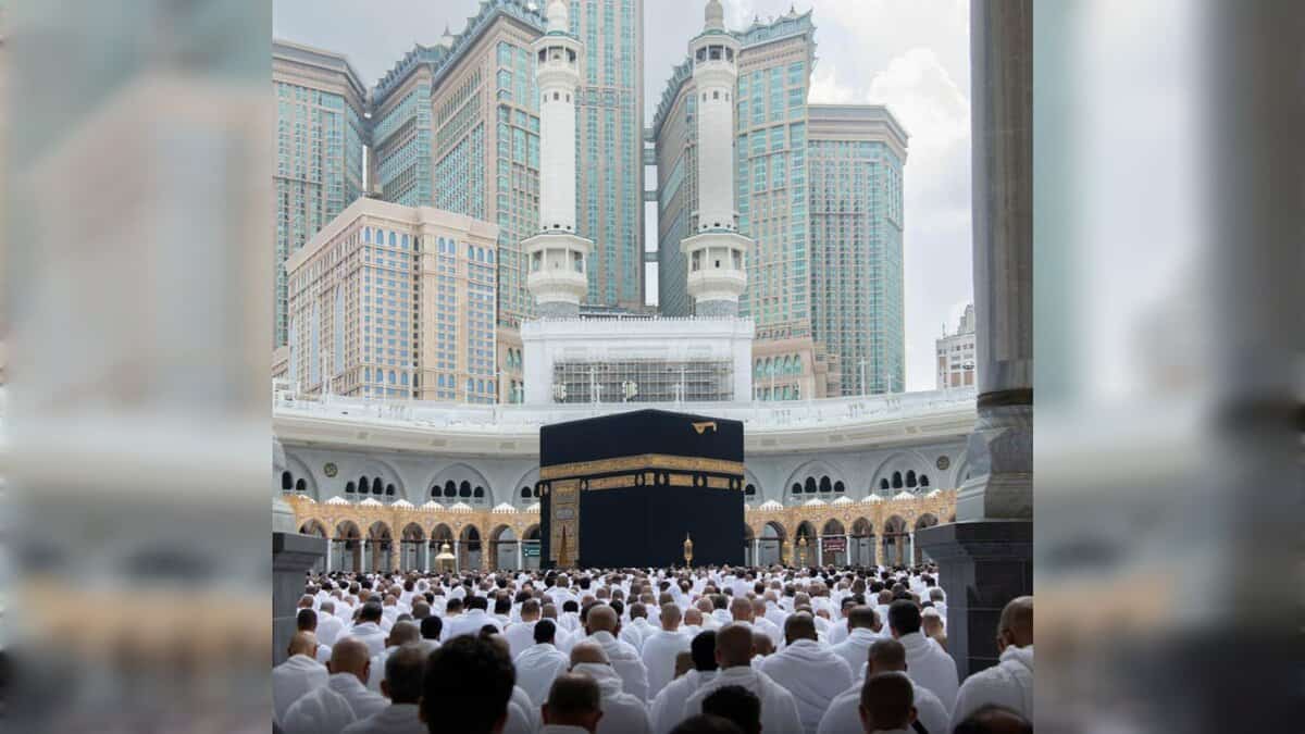 Pilgrims gathered around the Kaaba at the Grand Mosque with Makkah towers in the background.