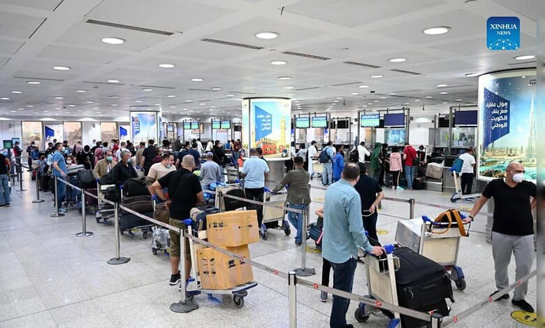 Travellers queue with luggage trolleys inside Kuwait International Airport’s departures hall.