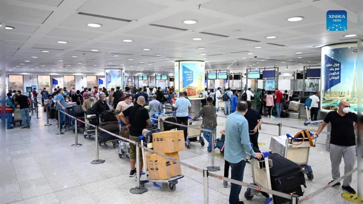 Travellers queue with luggage trolleys inside Kuwait International Airport’s departures hall.