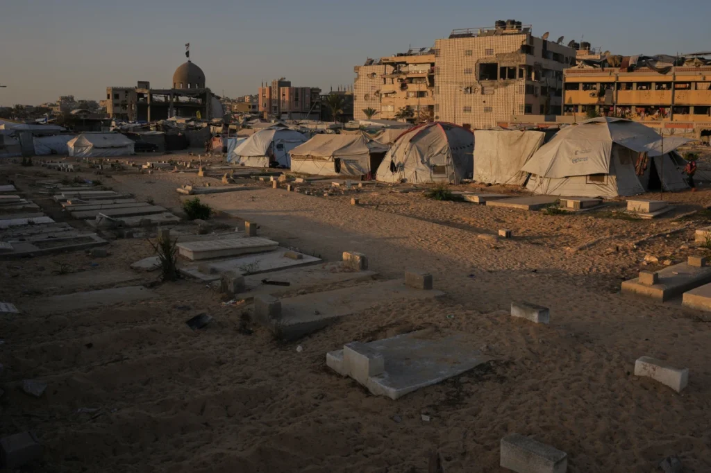 Makeshift tents for displaced Palestinians set up beside graves in a Khan Younis cemetery at sunset, southern Gaza Strip.