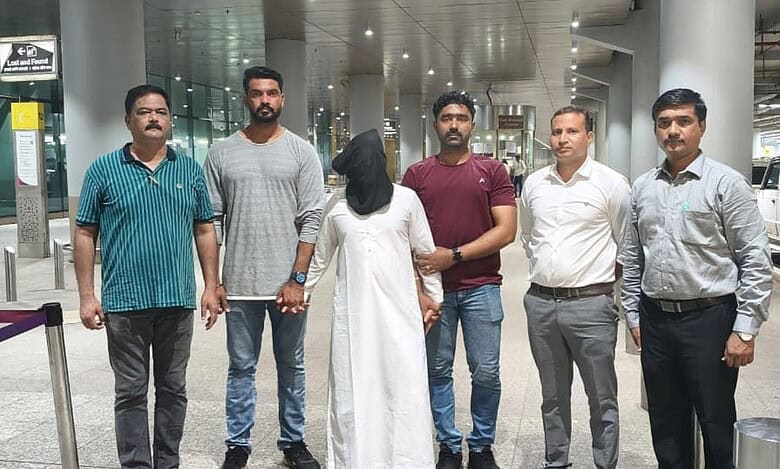 Mumbai Police personnel escort an accused after his deportation from the UAE at the airport.