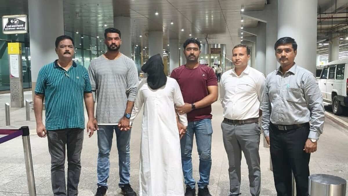 Mumbai Police personnel escort an accused after his deportation from the UAE at the airport.