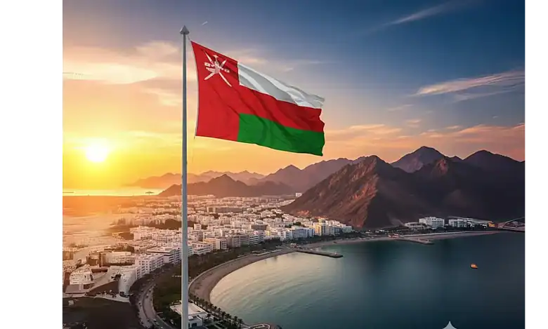 Omani flag waving over Muscat city at sunset with mountains in the background.