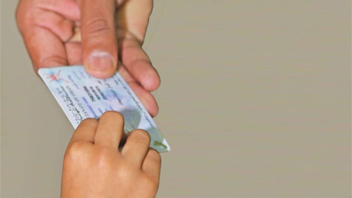 A person handing over an Oman residence card.