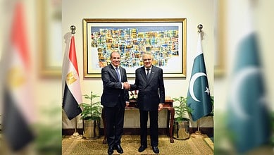 Egyptian and Pakistani foreign ministers shake hands in Islamabad with national flags behind them.