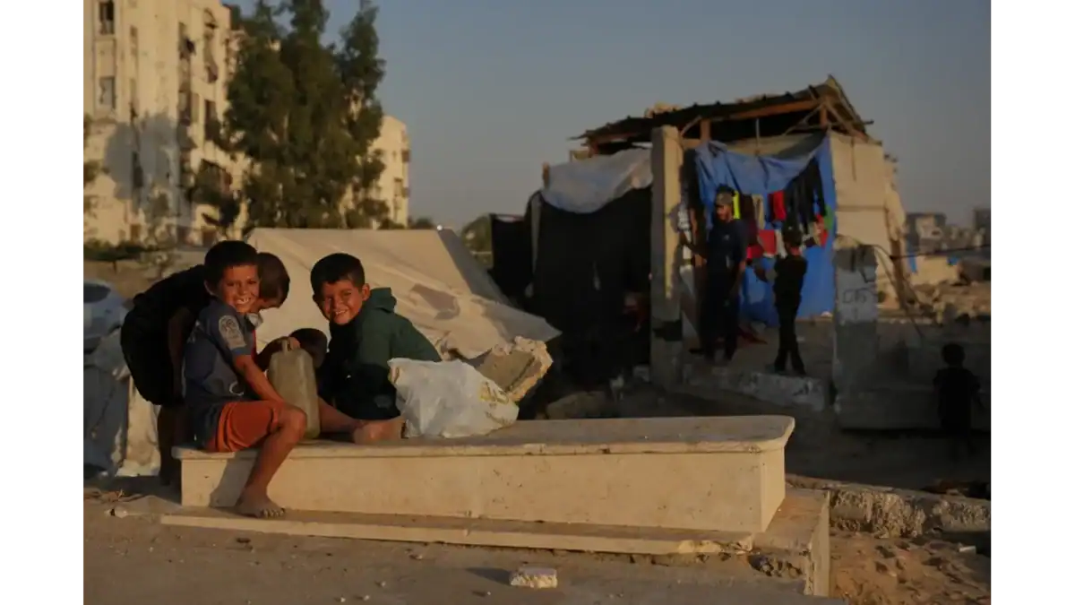Palestinian children sitting on a grave near makeshift tents in a Khan Younis cemetery, southern Gaza Strip.