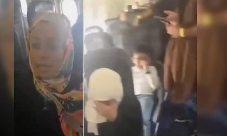 Passengers sit inside a crowded aircraft, with women and children visibly distressed during prolonged delay.