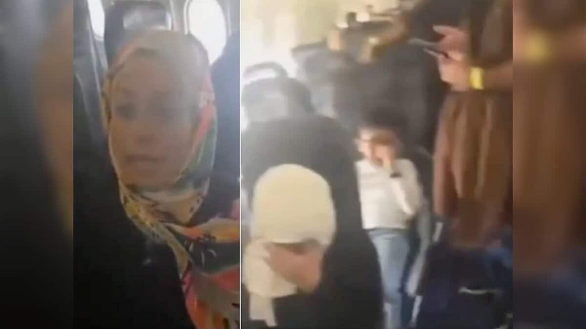 Passengers sit inside a crowded aircraft, with women and children visibly distressed during prolonged delay.