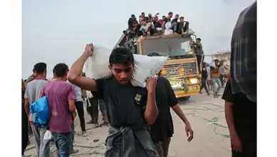 Palestinians carry aid parcels in northern Gaza as others crowd atop a truck near the Zikim crossing.