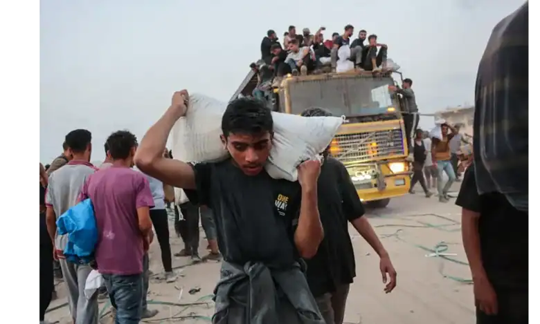 Palestinians carry aid parcels in northern Gaza as others crowd atop a truck near the Zikim crossing.