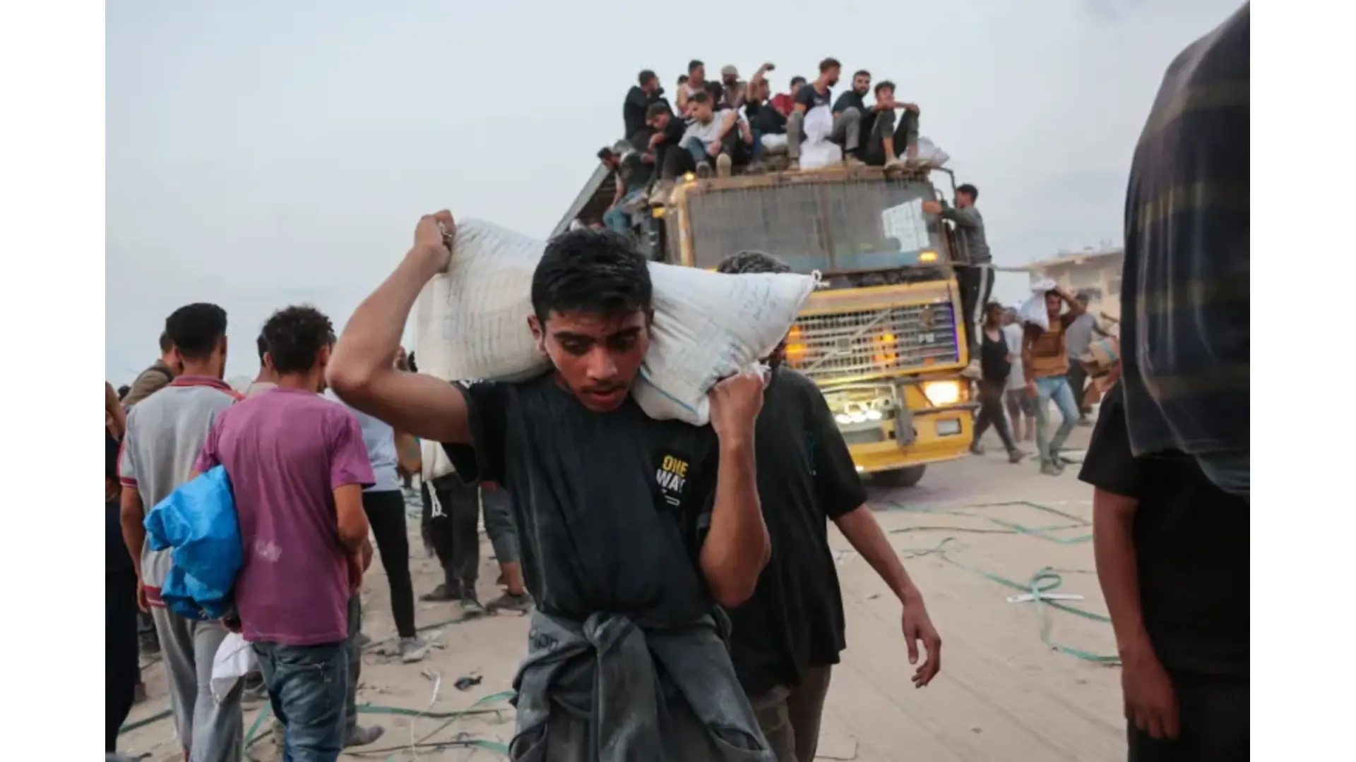 Palestinians carry aid parcels in northern Gaza as others crowd atop a truck near the Zikim crossing.