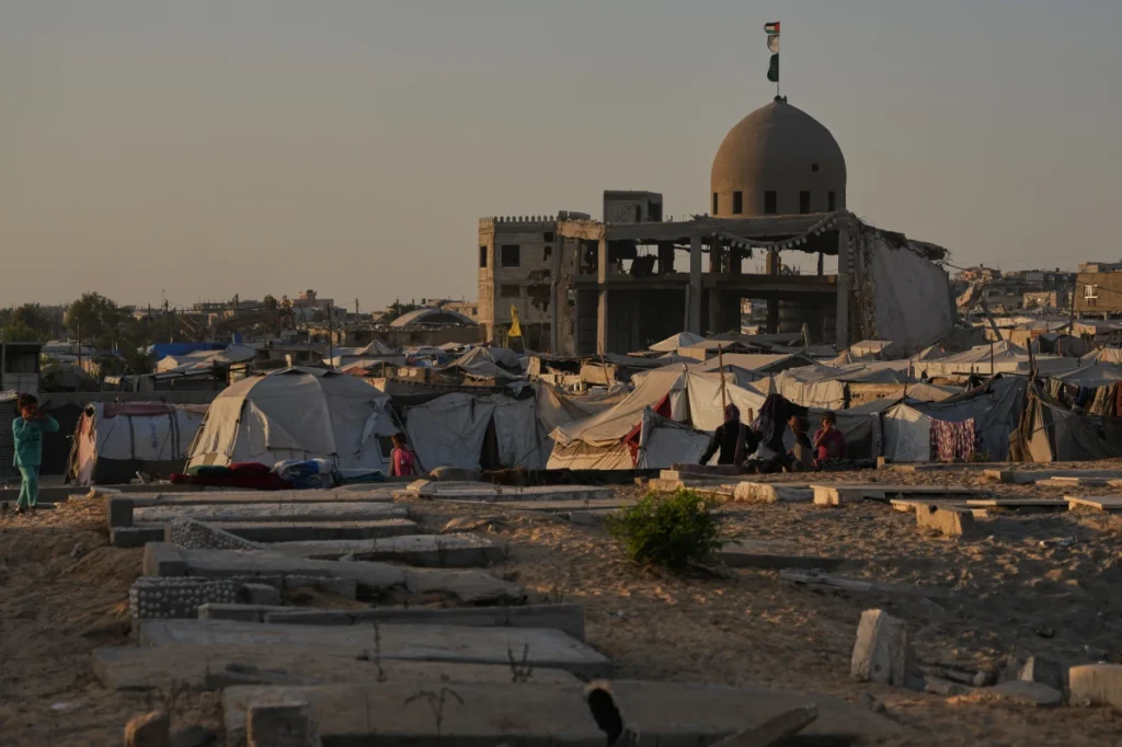 Palestinians stand beside makeshift tents set up among graves in a Khan Younis cemetery, southern Gaza Strip.