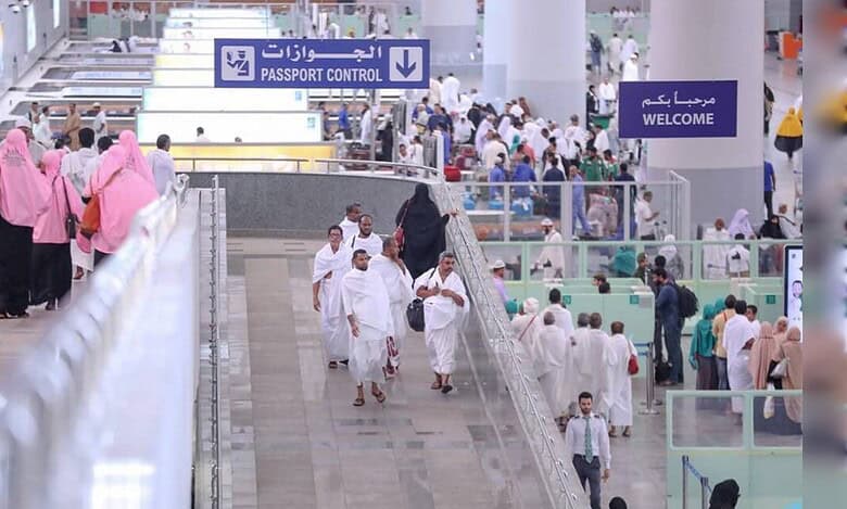Pilgrims walking through a busy airport passport control area during Haj arrivals.