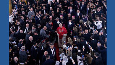 Pope Leo XIV walking through a crowd inside the Cathedral of the Holy Spirit in Istanbul as clergy and attendees greet and photograph him.