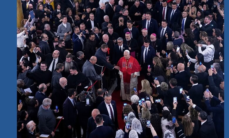 Pope Leo XIV walking through a crowd inside the Cathedral of the Holy Spirit in Istanbul as clergy and attendees greet and photograph him.
