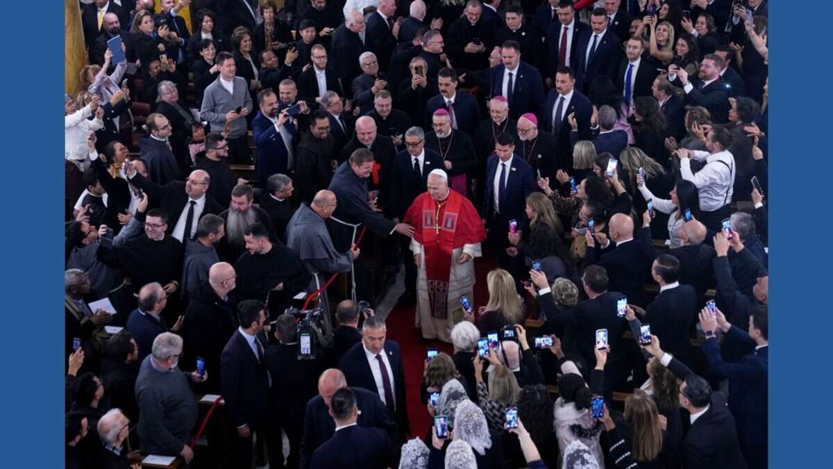 Pope Leo XIV walking through a crowd inside the Cathedral of the Holy Spirit in Istanbul as clergy and attendees greet and photograph him.