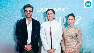 Three individuals pose for a photo at the launch event of DAMAC Islands 2 in Dubai.