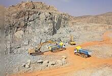 Aerial view of heavy machinery and trucks operating at a mining site in a rocky desert area in Saudi Arabia