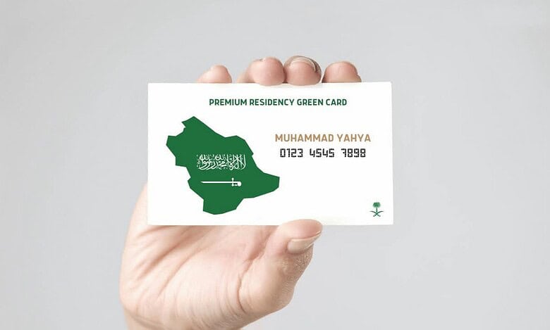 A person holds a Saudi Arabia Premium Residency Green Card showing the map of the Kingdom and the name Muhammad Yahya.