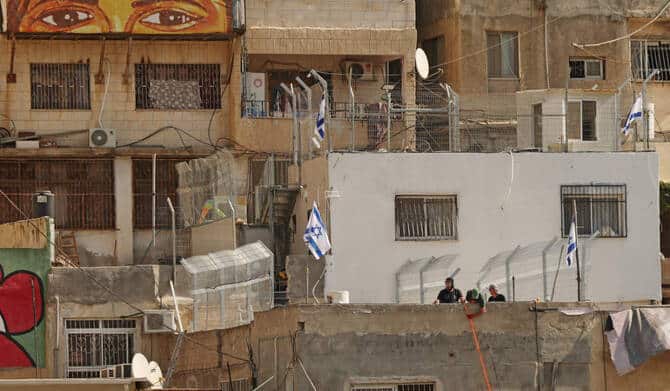 Israeli settlers raise flags on the roof of a house in Silwan, East Jerusalem, after a Palestinian family was evicted by police.