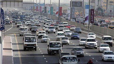 Heavy traffic on Sheikh Zayed Road in central Dubai with multiple lanes filled with cars and trucks.