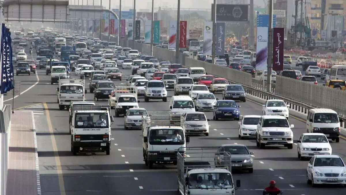 Heavy traffic on Sheikh Zayed Road in central Dubai with multiple lanes filled with cars and trucks.