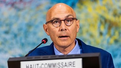 A UN human rights official speaking at a podium with a microphone.