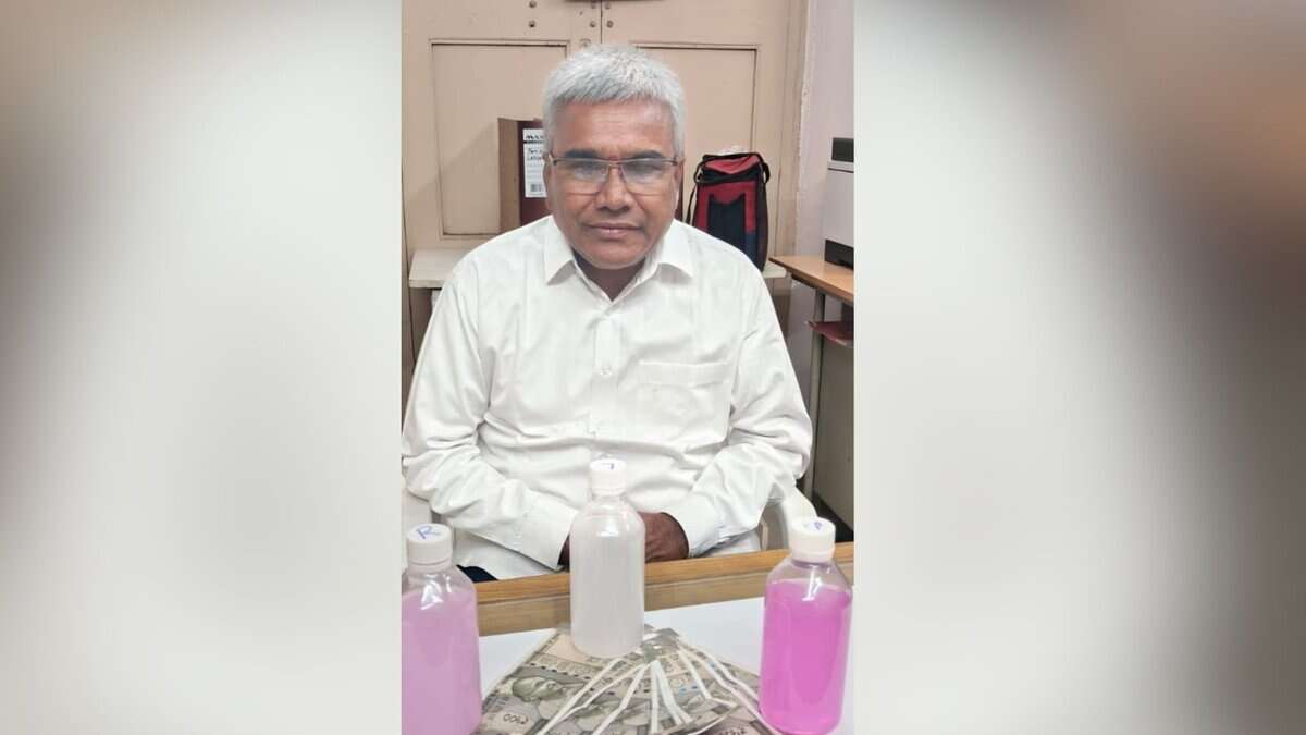 Image shows man in a white shirt with cash and bottles with pink fluid.