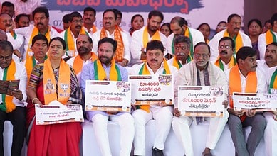 Political leaders wearing orange and green sashes sit on a stage holding signs with Telugu text and numerical figures during what appears to be a BJP party rally or demonstration.
