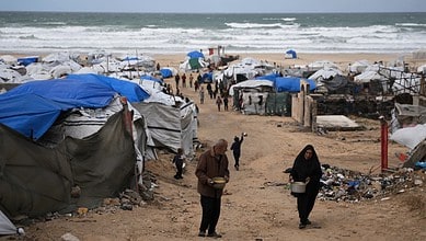 Palestinians receive donated food at a temporary camp for displaced people, on the beach near the port of Gaza City. (AP Photo/Jehad Alshrafi)