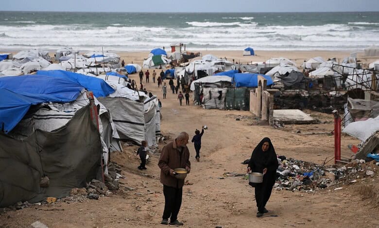 Palestinians receive donated food at a temporary camp for displaced people, on the beach near the port of Gaza City. (AP Photo/Jehad Alshrafi)
