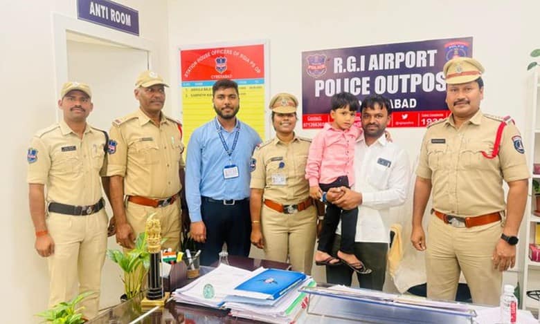 Police officers pose with civilians and a young child at the RGI Airport Police Outpost in Hyderabad.