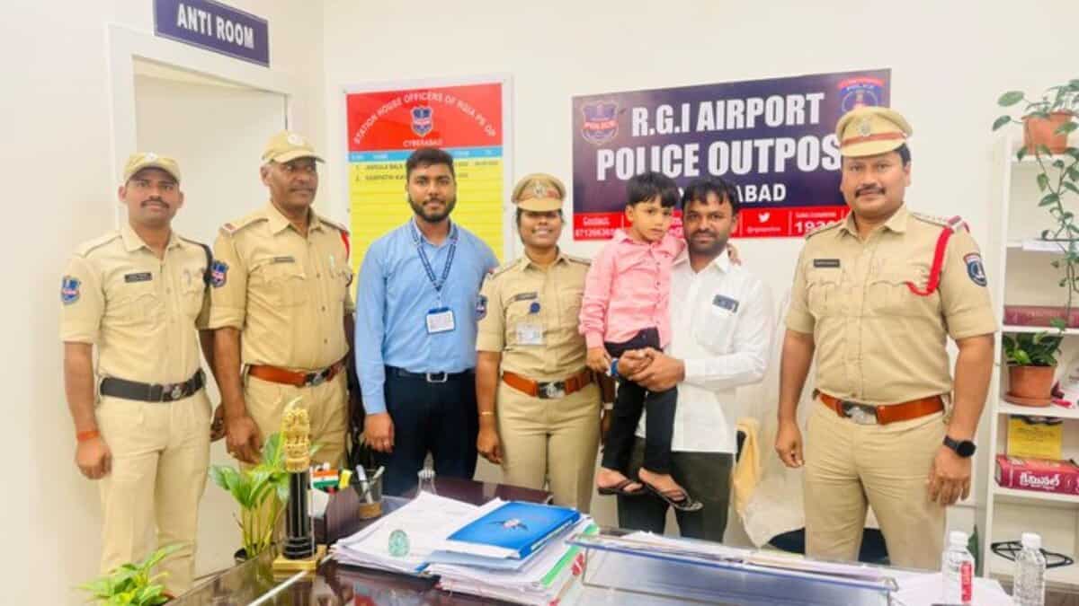 Police officers pose with civilians and a young child at the RGI Airport Police Outpost in Hyderabad.