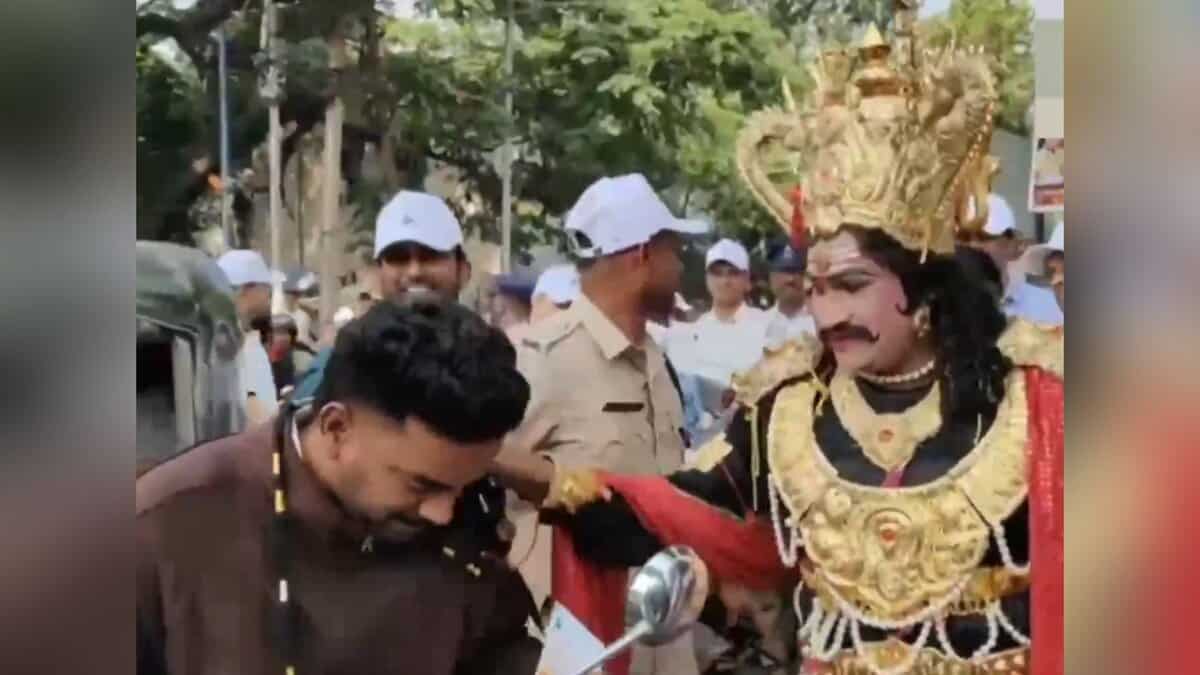 Image shows a man dressed at Yamraj handing garlanding a man
