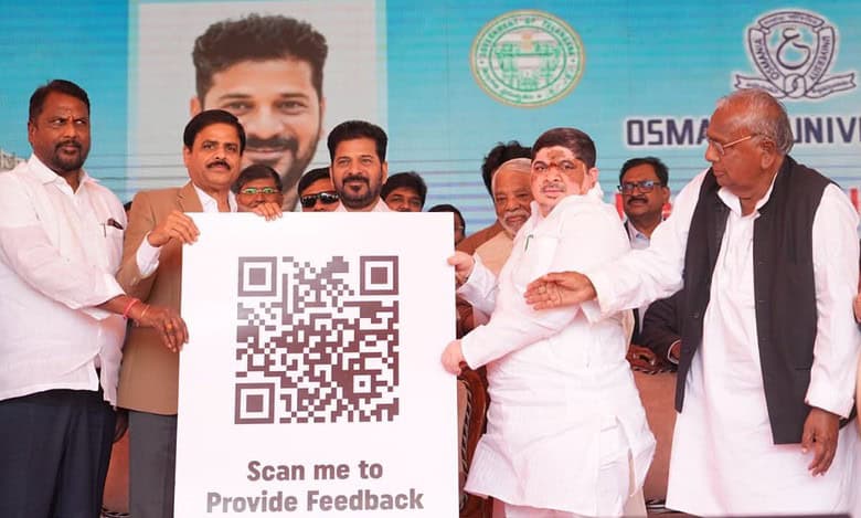 Government officials display a large QR code sign reading "Scan me to Provide Feedback" at a public event with Osmania University branding visible in the background.