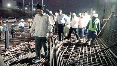 Construction site inspection with engineers and workers at night focusing on steel reinforcement.