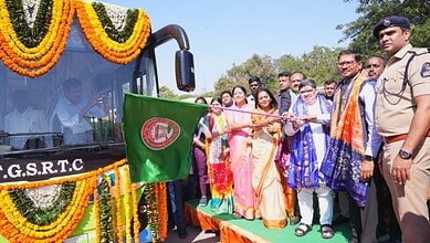 Officials and dignitaries inaugurate a decorated TGSRTC bus adorned with marigold flower garlands during a ceremonial event.