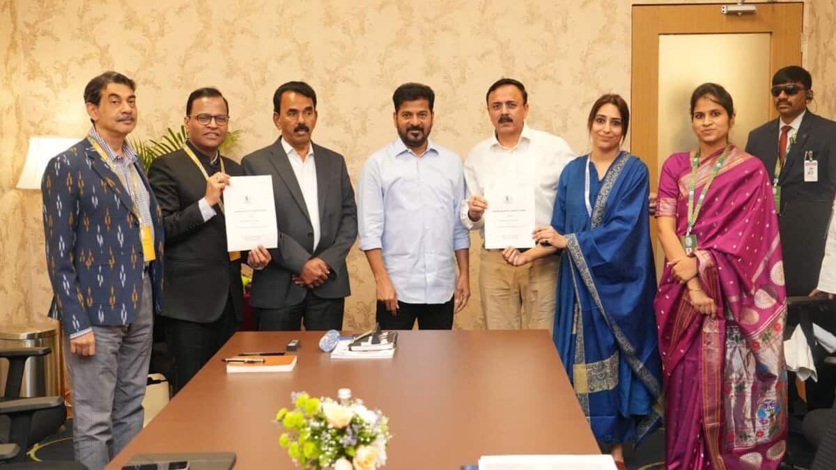 Group of eight professionals posing for a formal photo around a conference table, with two people holding documents, appearing to be at a signing ceremony or official meeting.