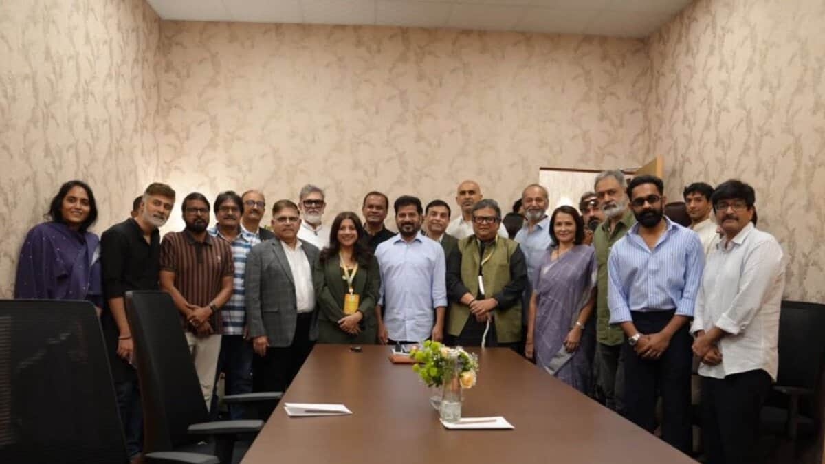 Large group of approximately 20 professionals posing together in a conference room around a long table with a flower centerpiece.