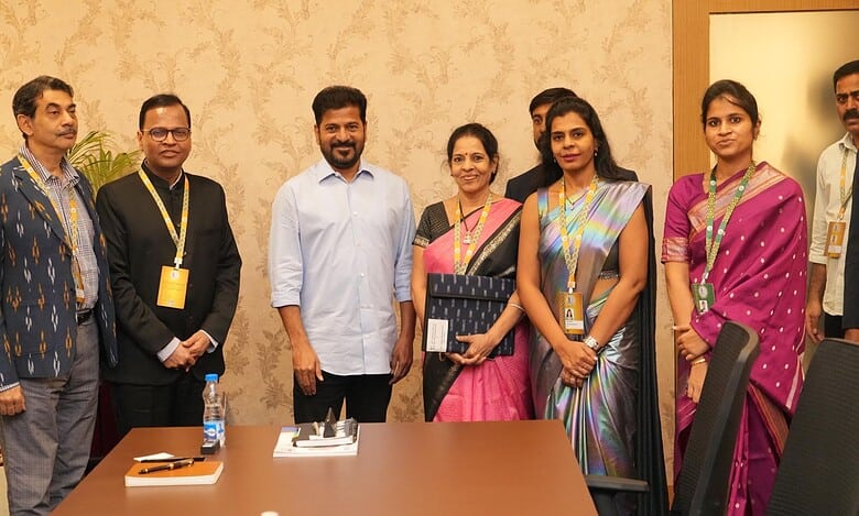 Seven professionals standing together in a conference room for a group photo, several wearing traditional Indian attire and conference badges