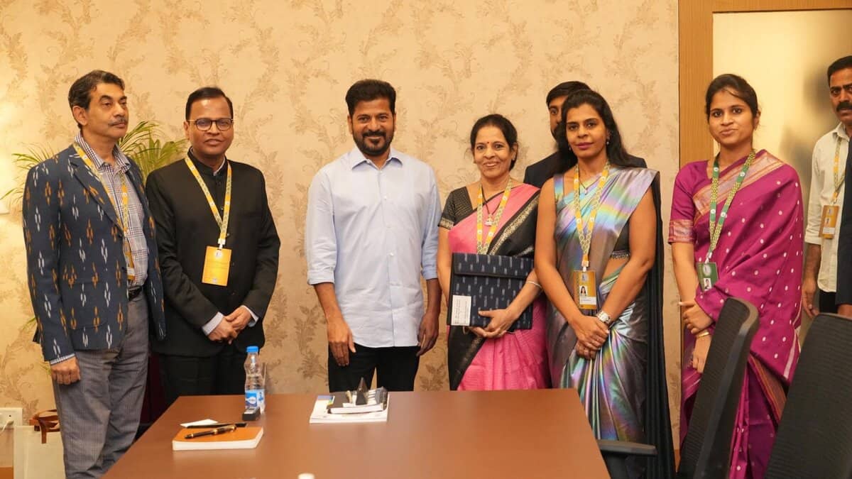 Seven professionals standing together in a conference room for a group photo, several wearing traditional Indian attire and conference badges