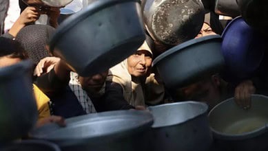 A Palestinian woman tries to get food (Bashar Taleb/AFP)