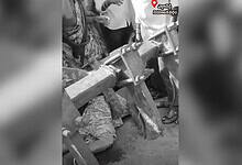 A black and white image showing a woman lying under a tractor.