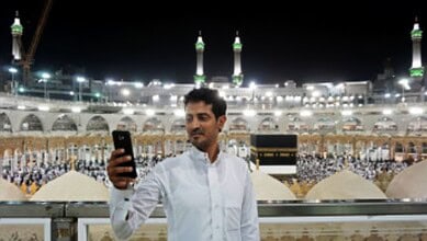 Man taking a photo on his phone at the Grand Mosque in Makkah.