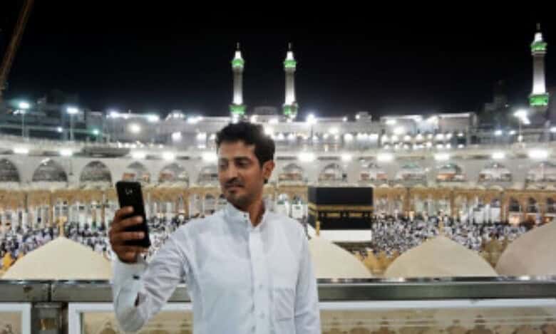 Man taking a photo on his phone at the Grand Mosque in Makkah.
