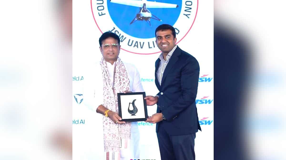 Image shows Minister Sridhar Babu accepting a memento infront of a white background