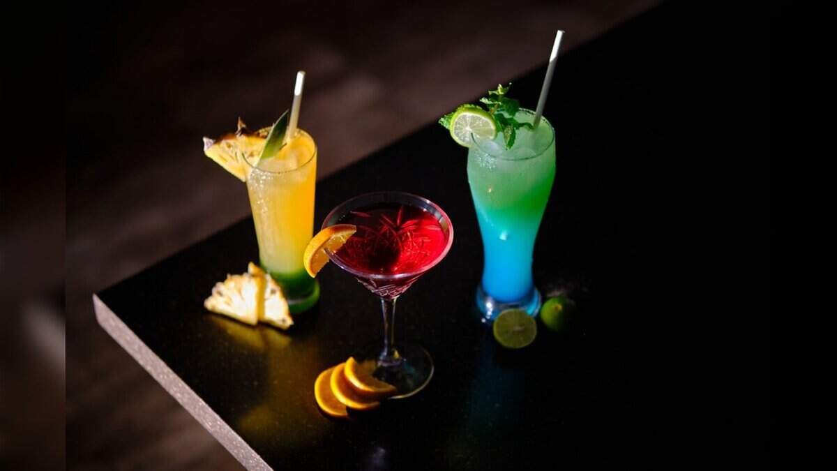 Glasses of colourful sweetened beverages served with fruit garnishes.