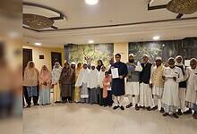 Pilgrims standing together in a hotel lobby holding flight papers.